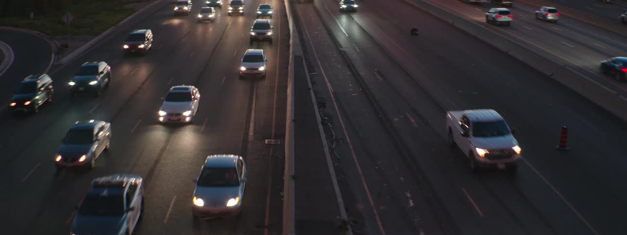 Cars and trucks travel in both directions on a multi lane highway at night