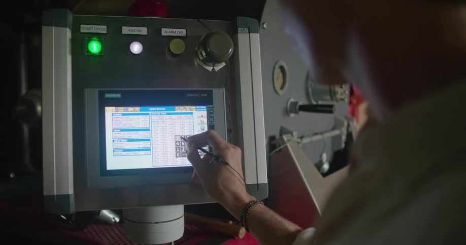 A man uses a stylus to enter data and calculations on a machine with touch screen display panel