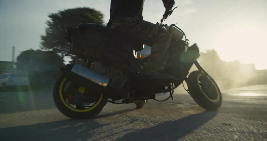 Man spinning on a small motorcycle on the streets of a neighborhood at morning