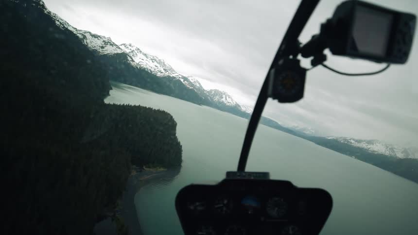A helicopter is flying over the lake as it snows