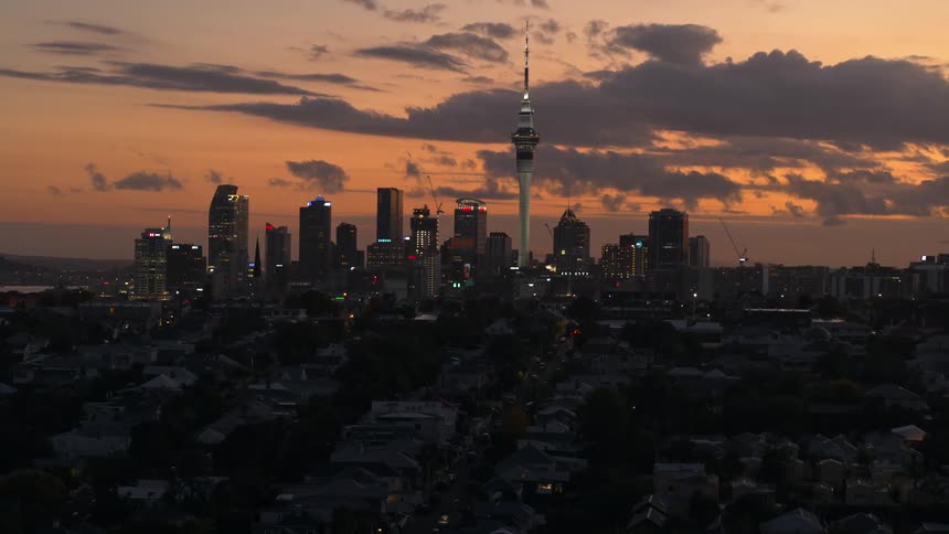 An aerial view of a suburban neighborhood with a skyline in the background at dusk