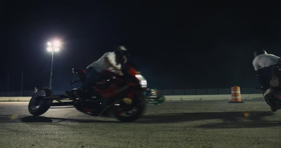 Three people go in a circle on their motorcycles at night