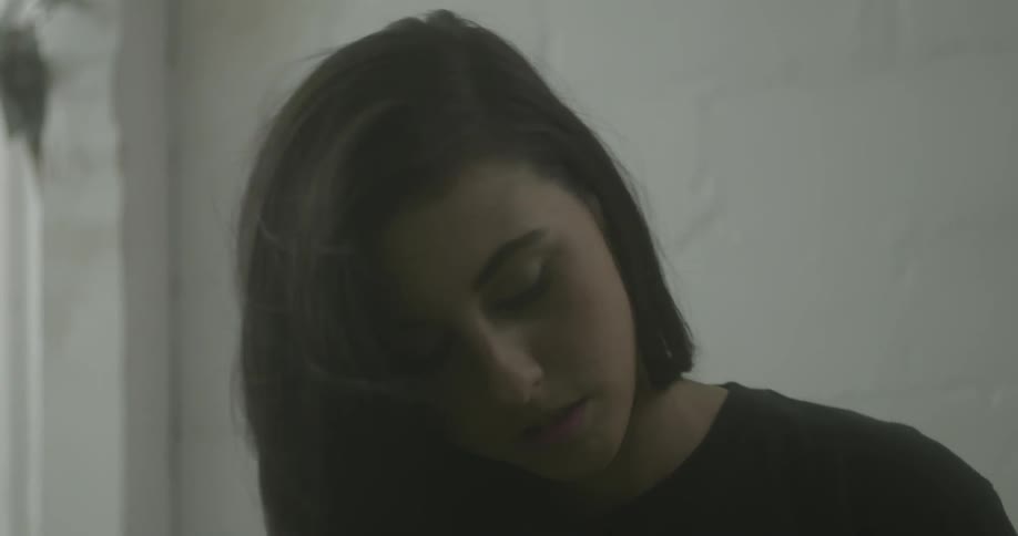 A dark haired woman looks around and then gets up