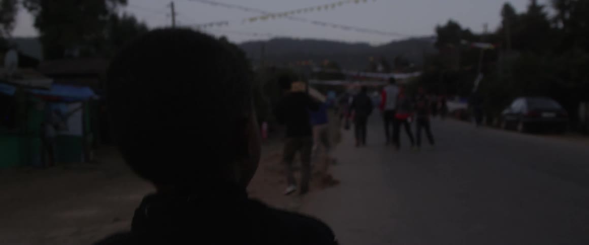 A boy walks down a dim street