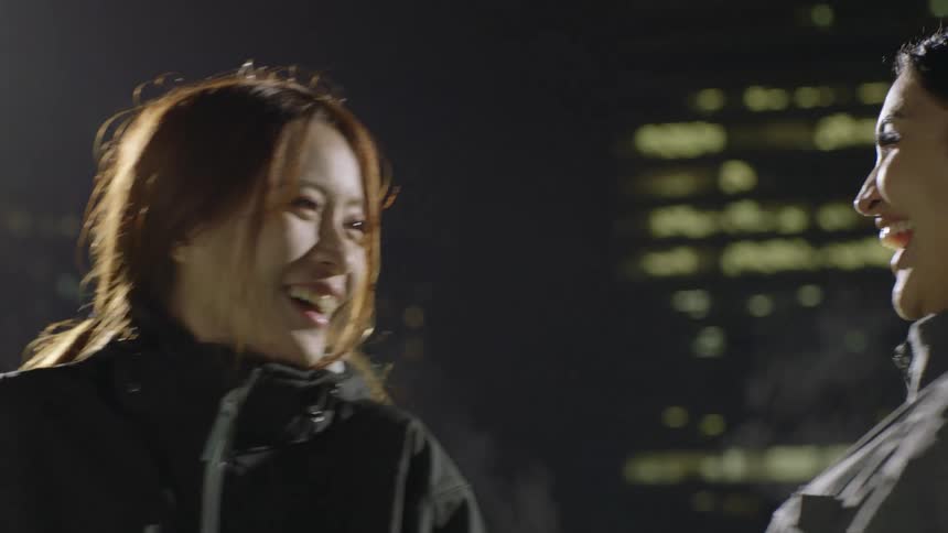 Happy friends wearing black clothes hug and talk in the city at night