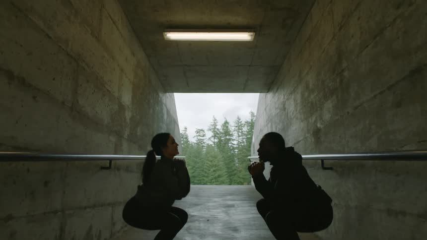 Friends working out together inside a concrete hallway