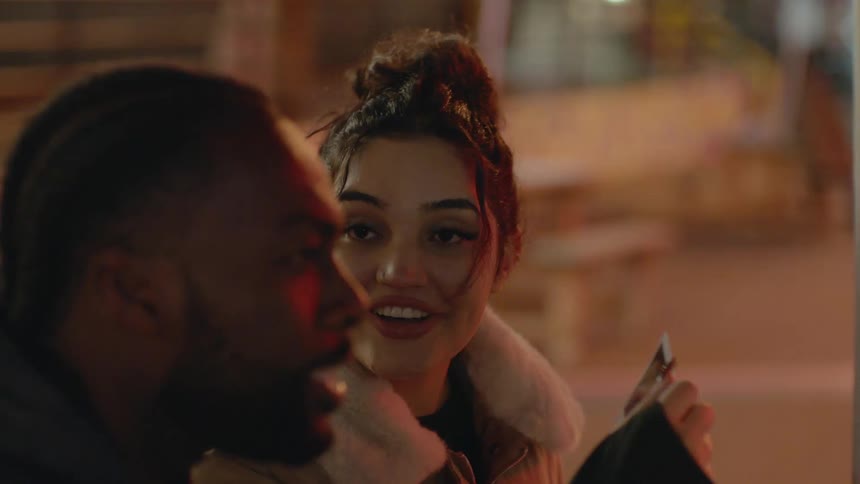 A few people are at an outdoor table smiling and talking as they pass a photograph around