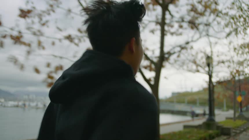 A man jogs along the coast in a city on a cloudy day