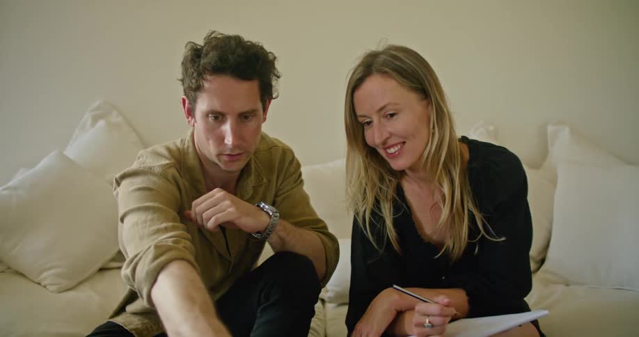Young couple looking at a laptop while sitting on a couch at home