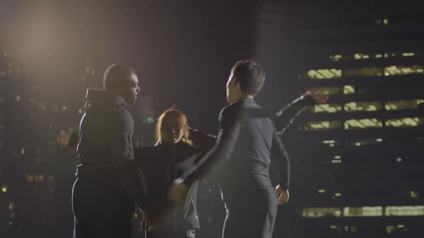 Group of friends wearing black sports clothes celebrates in the city at night