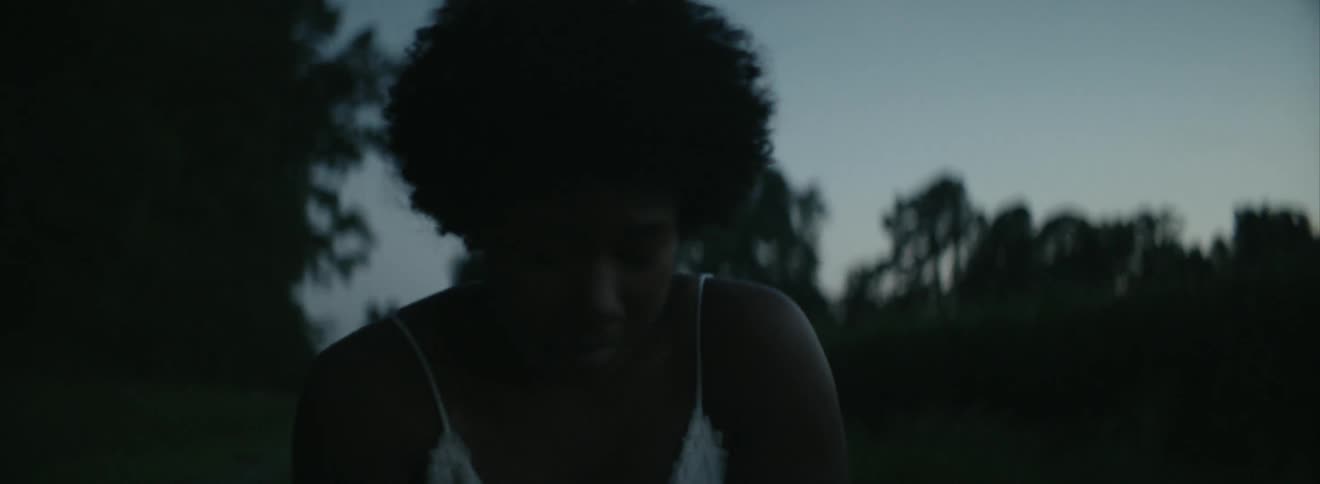 A woman is crouched on a field at dawn