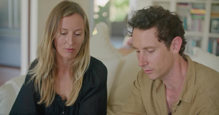 Man and woman sit on couch discussing flyers