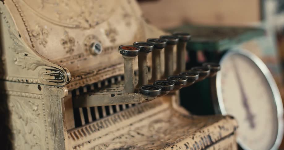 A small antique register sits next to a scale with a large round dial face
