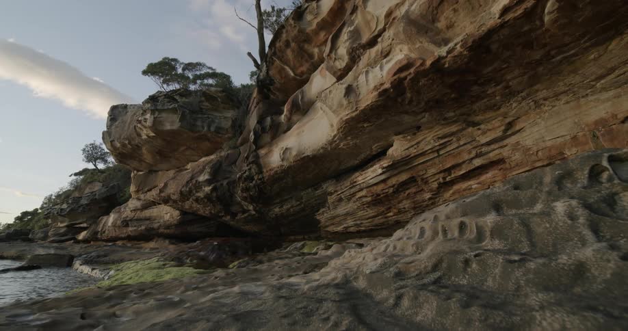 The water splashes against the cliff covered shore