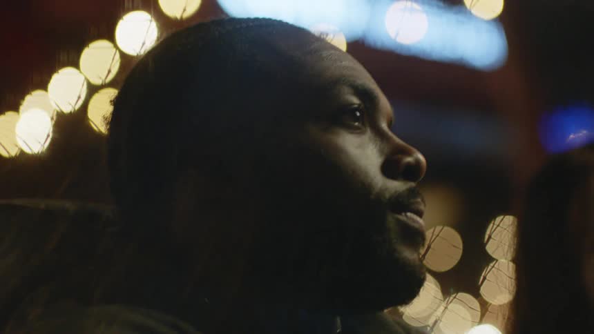 Man sitting with friends in an outdoors restaurant in the city at night