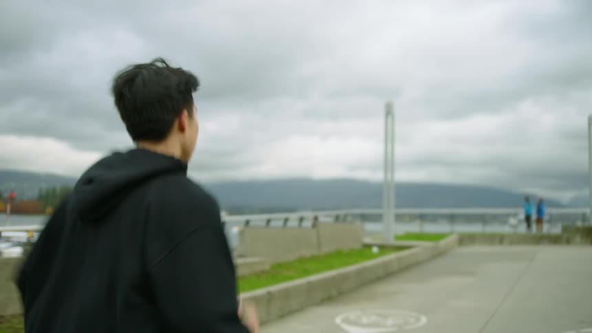 Man runs along street near seaplanes across water from forest with skyscrapers in background on a fall day