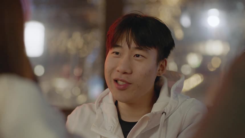 Man with white jacket sits at table talks with his friends at restaurant