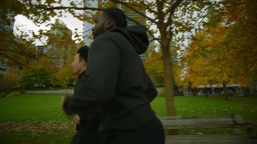 Friends jog through city park before racing each other
