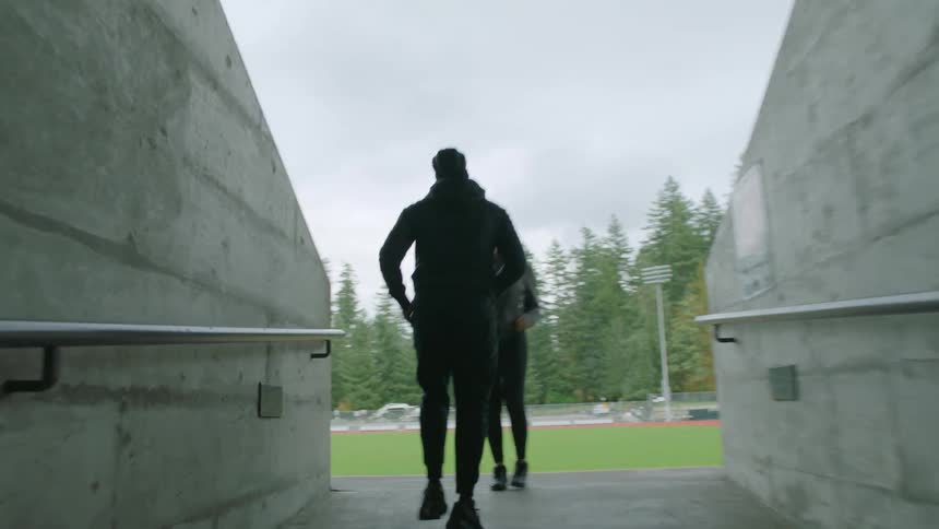 Man jogs through a hallway to meet a friend inside a stadium
