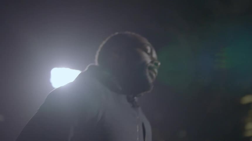 Tired man wearing black clothes stands in a stadium on the city at night