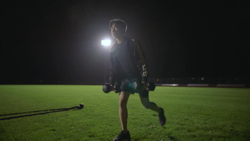 A group of people use weights and ropes to exercise on a cool night