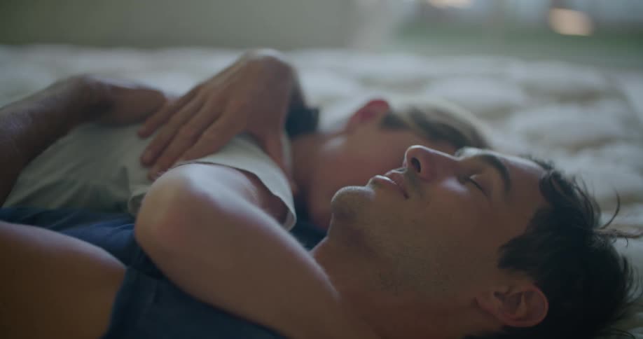 Young couple hugging and smiling while resting on bed at home in the morning