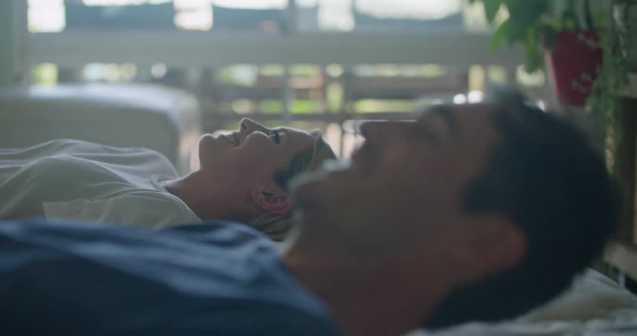 Young couple resting in the bed look at each other and laugh