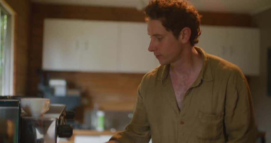 Young man pressing ground coffee on a espresso machine at home