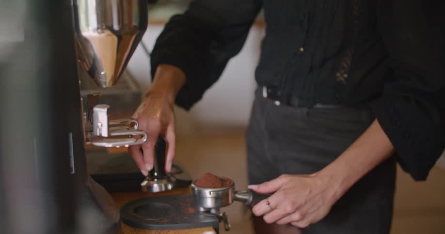 A woman uses a machine to prepare coffee