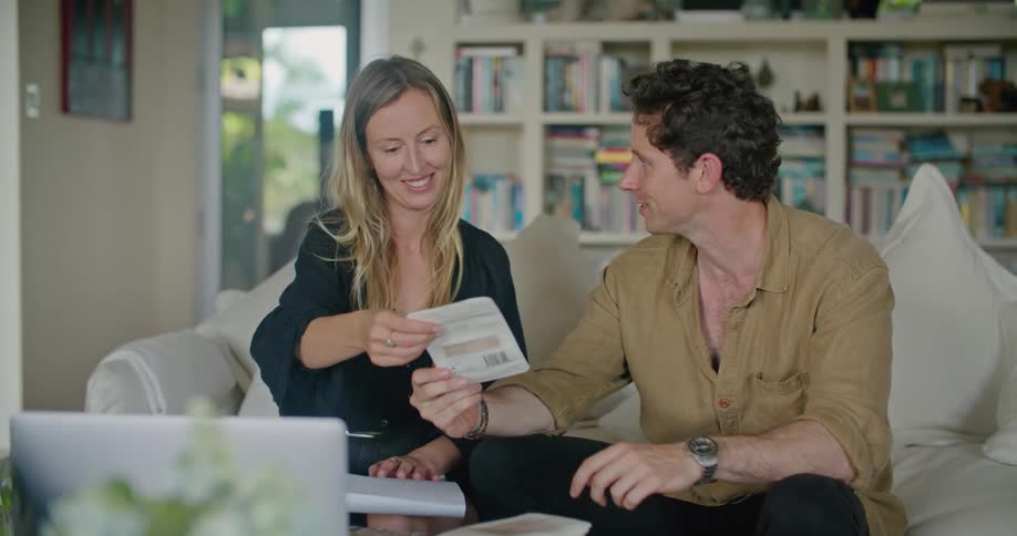 Young couple sitting on a couch looking at receipts