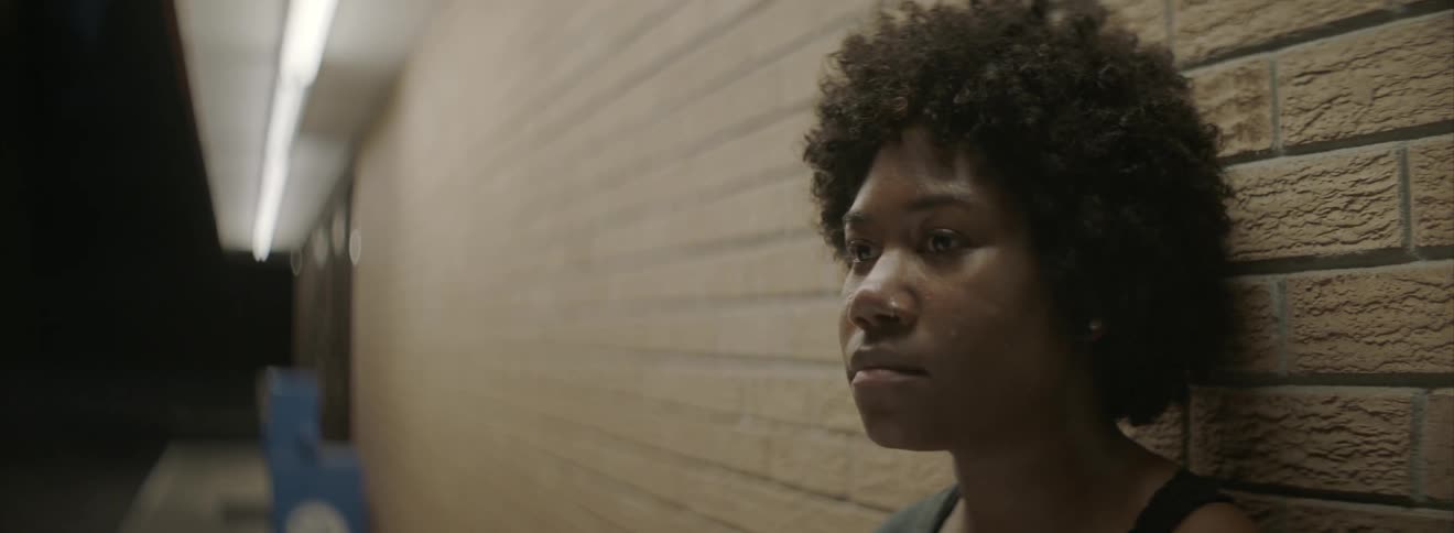 Woman standing against a building at night stares off
