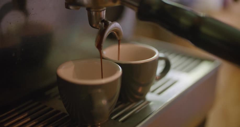A cappuccino machine is filling two mugs