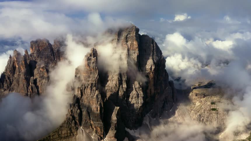 Dense clouds hovering around a rocky mountain range in the daytime