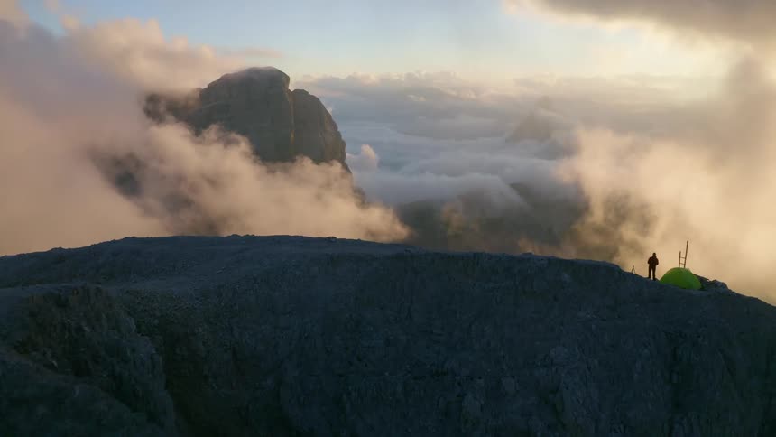 A man is standing on the mountain peak