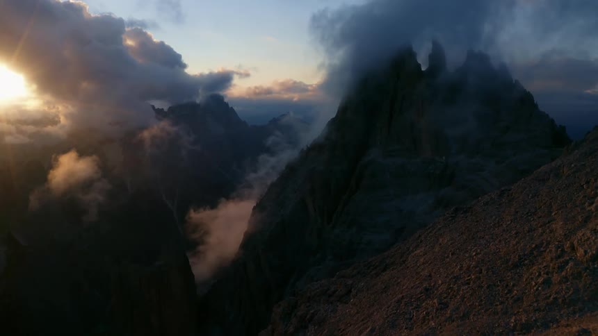 Sunlight peaks through dense clouds over a mountain range