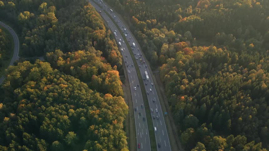 Aerial view of traffic on a busy highway and trees along the side of the road in fall colors
