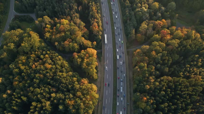 Aerial view of a busy highway and trees along the side of the road in fall colors