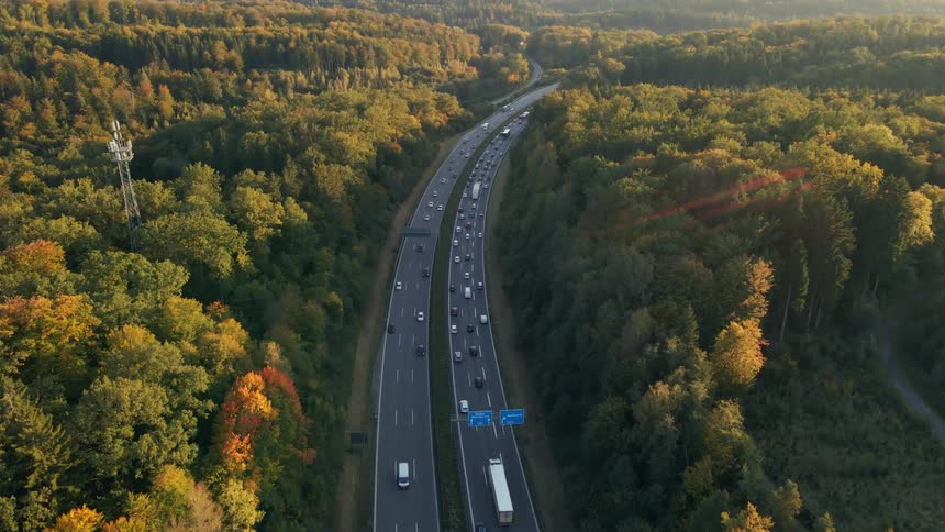 Aerial view of a busy highway and trees along the side of the road in fall colors