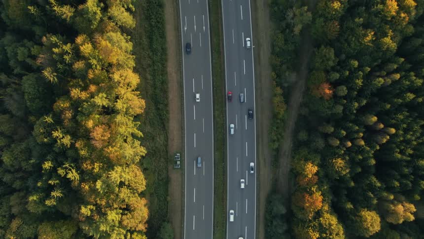Aerial view of trucks and cars driving on divided highway next to forest