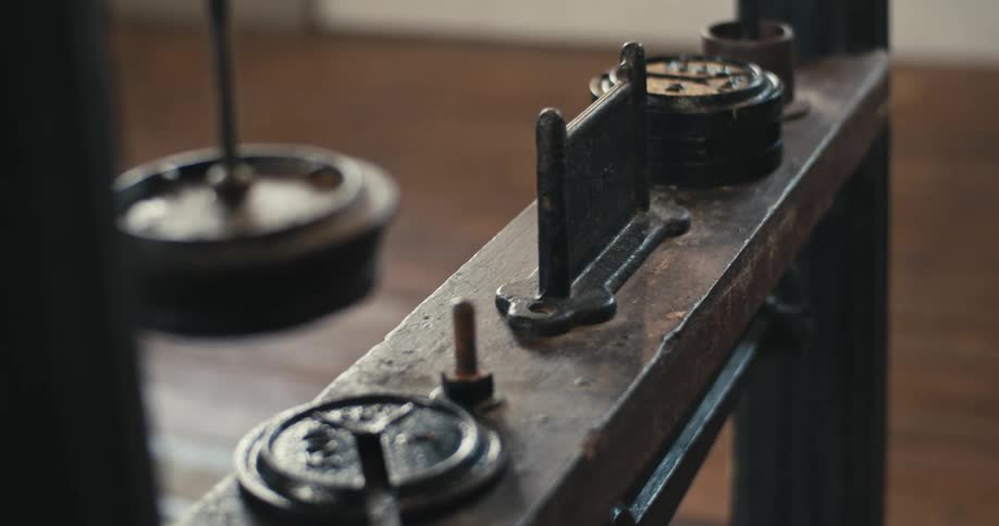 Metal parts sit on wooden shelf in wood floored room