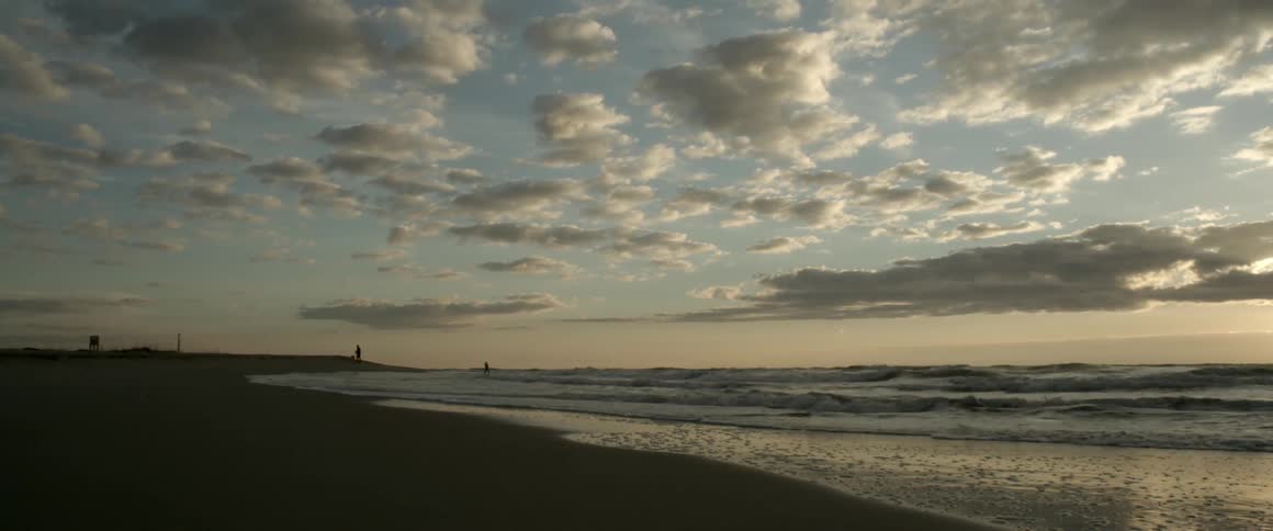 Waves roll into a beach at sunset
