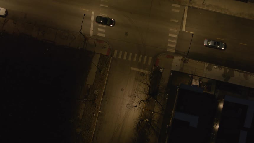 Vehicles drive through a suburban intersection at night