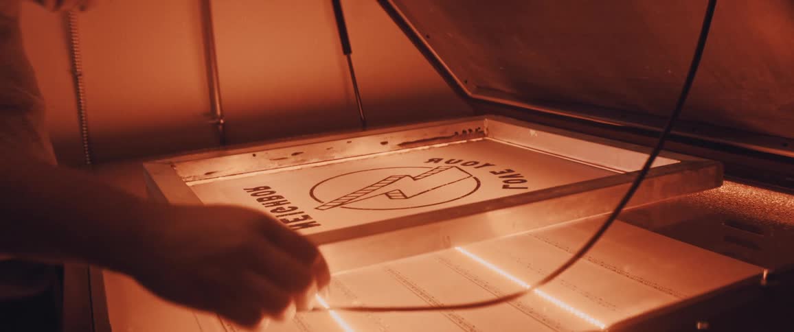Worker preps silk screen using machine