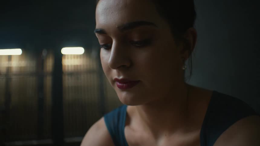 A woman leans forward in the dark room