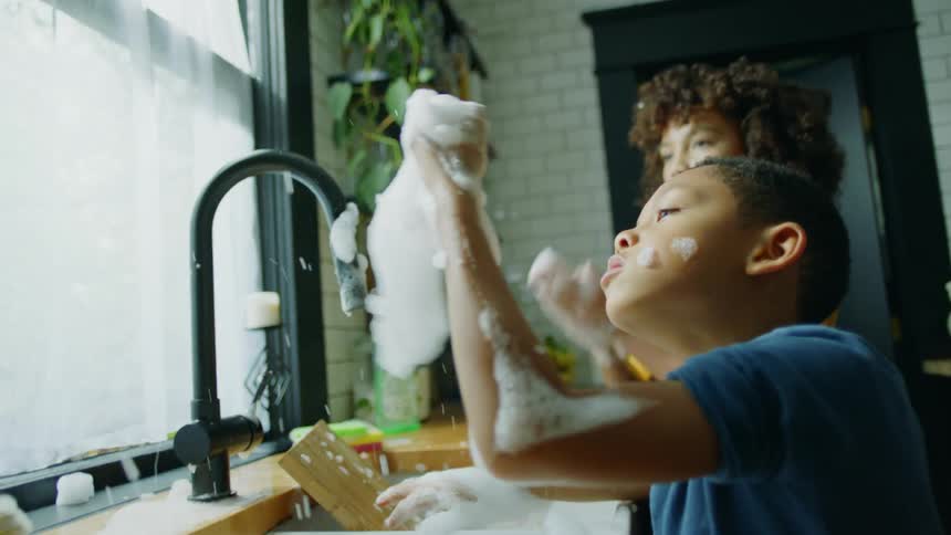 Two children play with bubbles in the sink