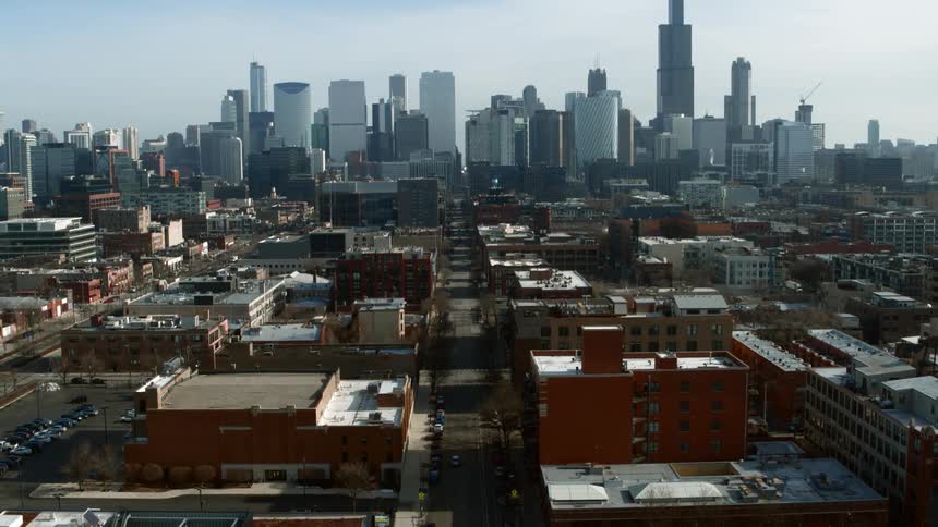 Cars line street leading through residential neighborhood toward city downtown