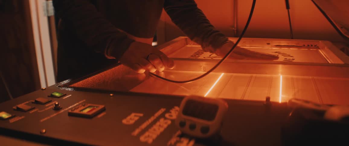 Man preps silkscreen panel on machine