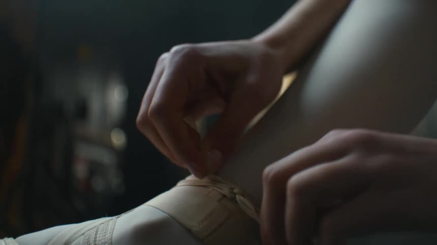 Ballerina sitting on the stage tying the laces of her shoes