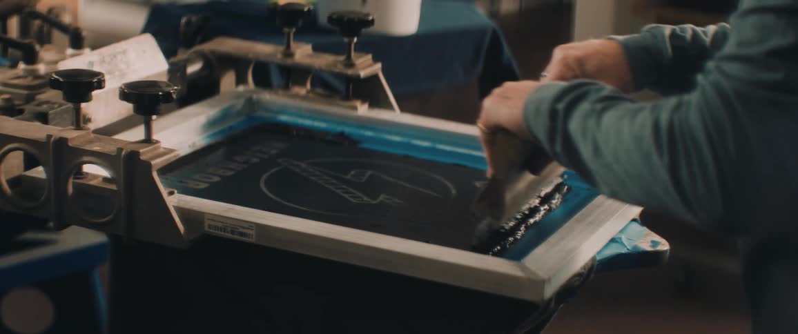 An employee using a screen printer