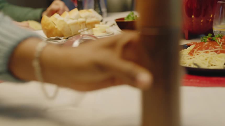 A woman spills her wine while reaching for something on the table